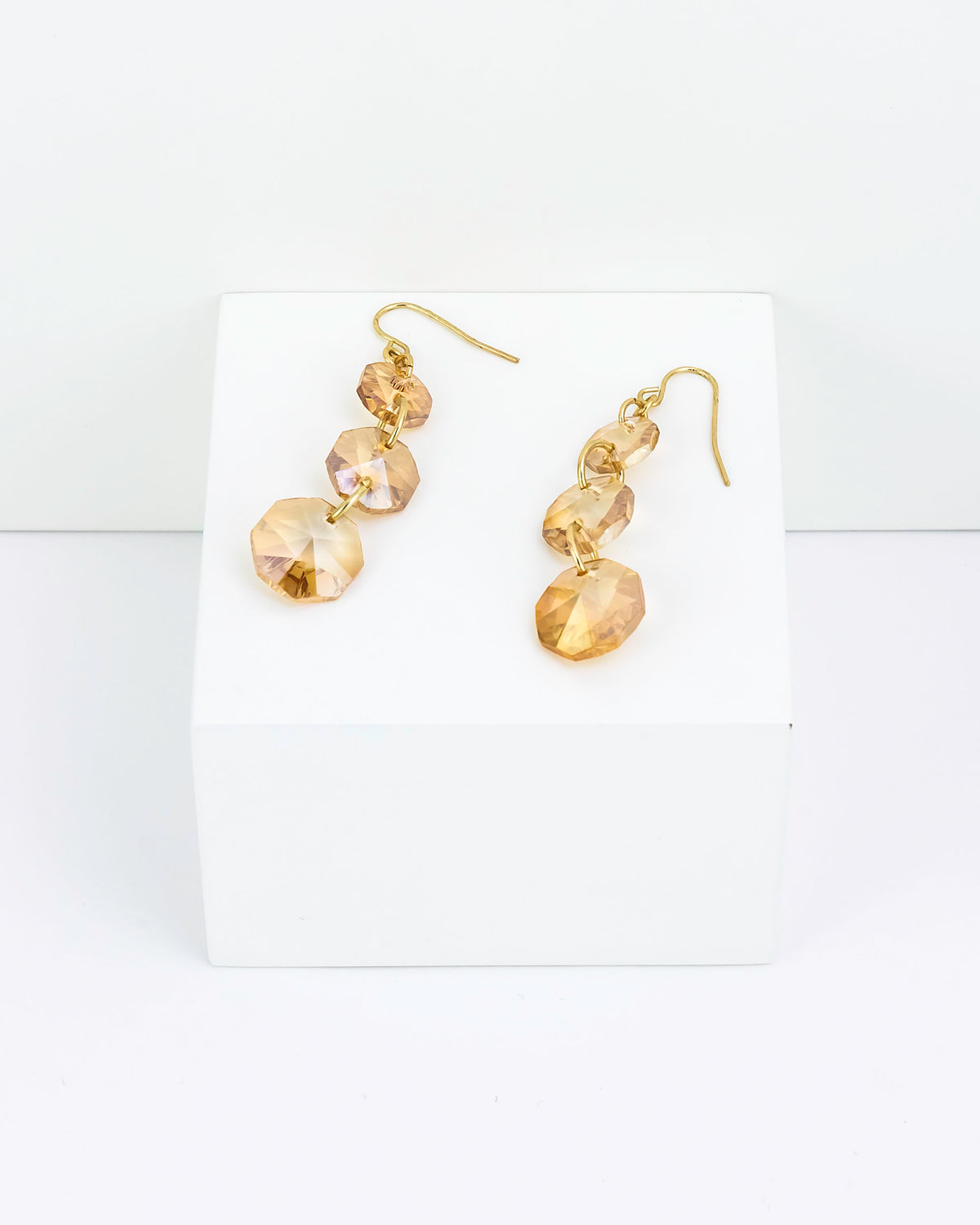 Gold earrings with clear gemstones on a white card