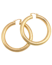 Pair of large worn-gold tubular hoop earrings with click-top closures overlapping on a white background.