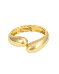 Polished gold-tone sculptural bypass hinged bangle bracelet on a white background.