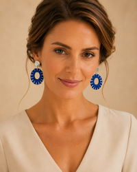 Model wearing worn-silver oval drop earrings with blue wrapped accents and an ivory blouse.