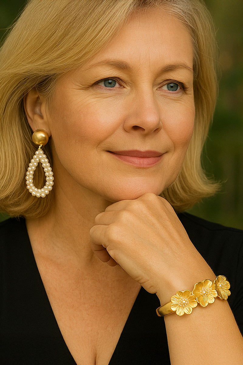 Woman wearing gold earrings and bracelet with a blurred green background