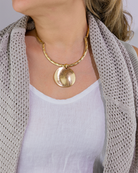 Gold necklace worn by a person with a neutral background
