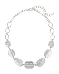 Worn-silver necklace with open links and textured organic discs, lobster clasp, and extender on a white background.