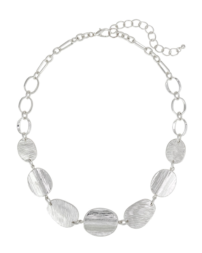 Worn-silver necklace with open links and textured organic discs, lobster clasp, and extender on a white background.
