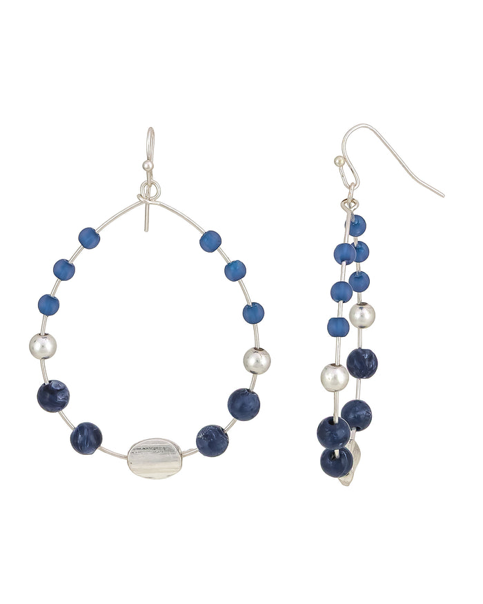 Blue beaded open hoop French-wire earrings with worn-silver accents on a white background.