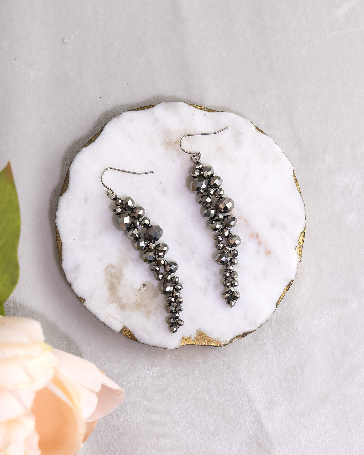 Pair of black beaded earrings on a white marble surface with a light gray background.
