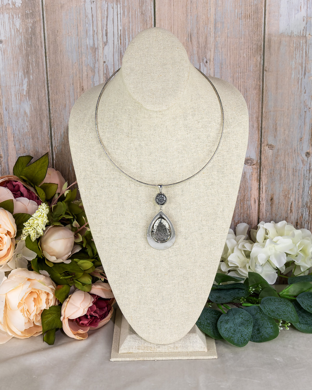 Necklace on a mannequin bust with flowers in the background