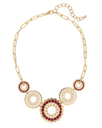 Gold necklace with circular designs and red stones on a white background