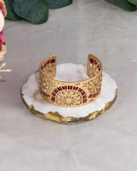 Gold bracelet with red wrapping on a white stone surface