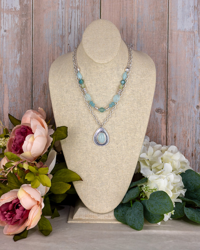 Necklace on a mannequin bust with flowers in the background