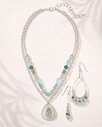 Jewelry set with necklace and earrings featuring blue and green beads on a white background