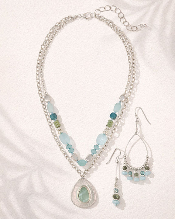Jewelry set with necklace and earrings featuring blue and green beads on a white background