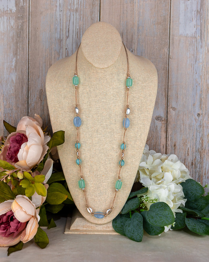 Necklace on a mannequin bust with flowers in the background