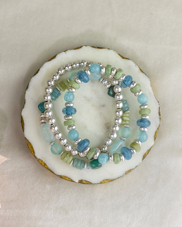 Two beaded bracelets on a white shell with a beige background