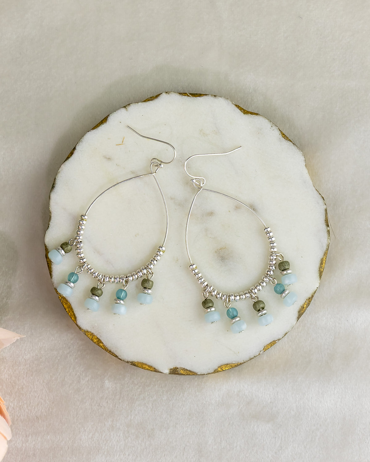 Silver hoop earrings with bead accents on a marble surface