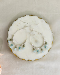 Silver hoop earrings with bead accents on a marble surface