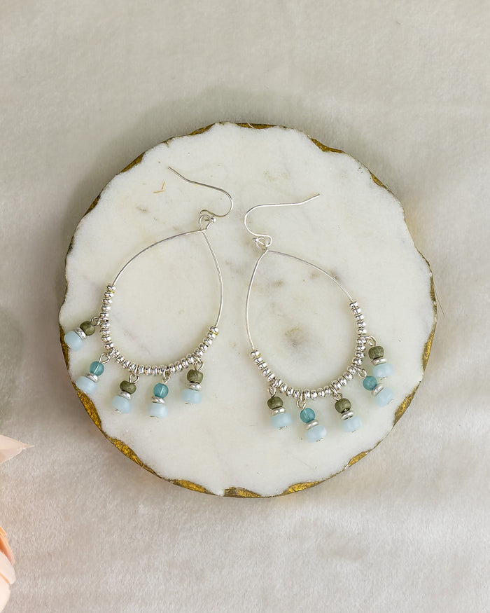 Silver hoop earrings with bead accents on a marble surface