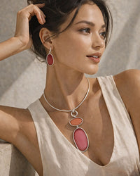 Woman wearing a necklace with pink pendant against a neutral background