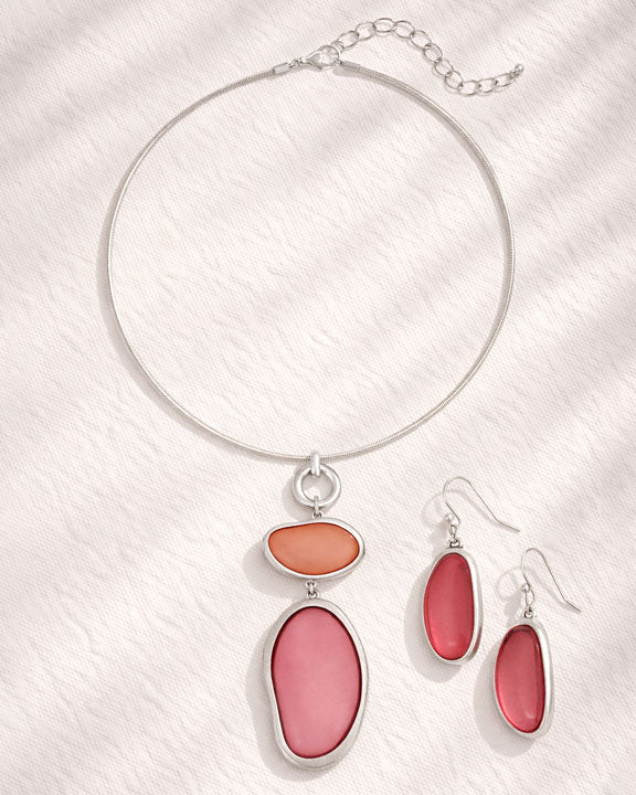 Necklace and earrings with pink and orange stones on a white background