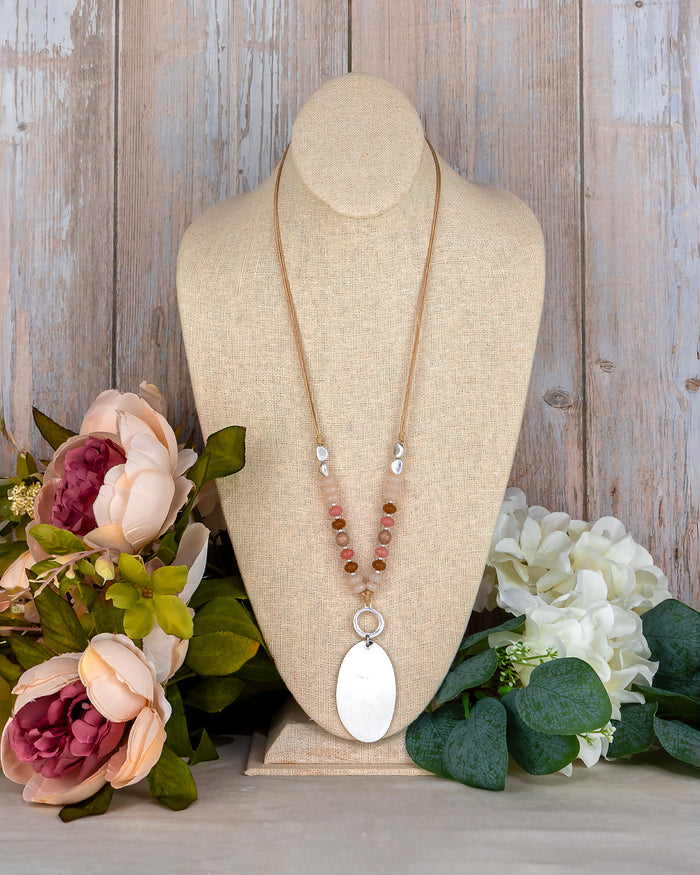 Necklace on a mannequin bust with flowers on a wooden background