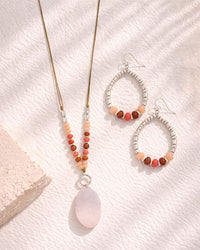 Beaded necklace and earrings on a textured white surface