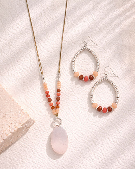 Beaded necklace and earrings on a textured white surface
