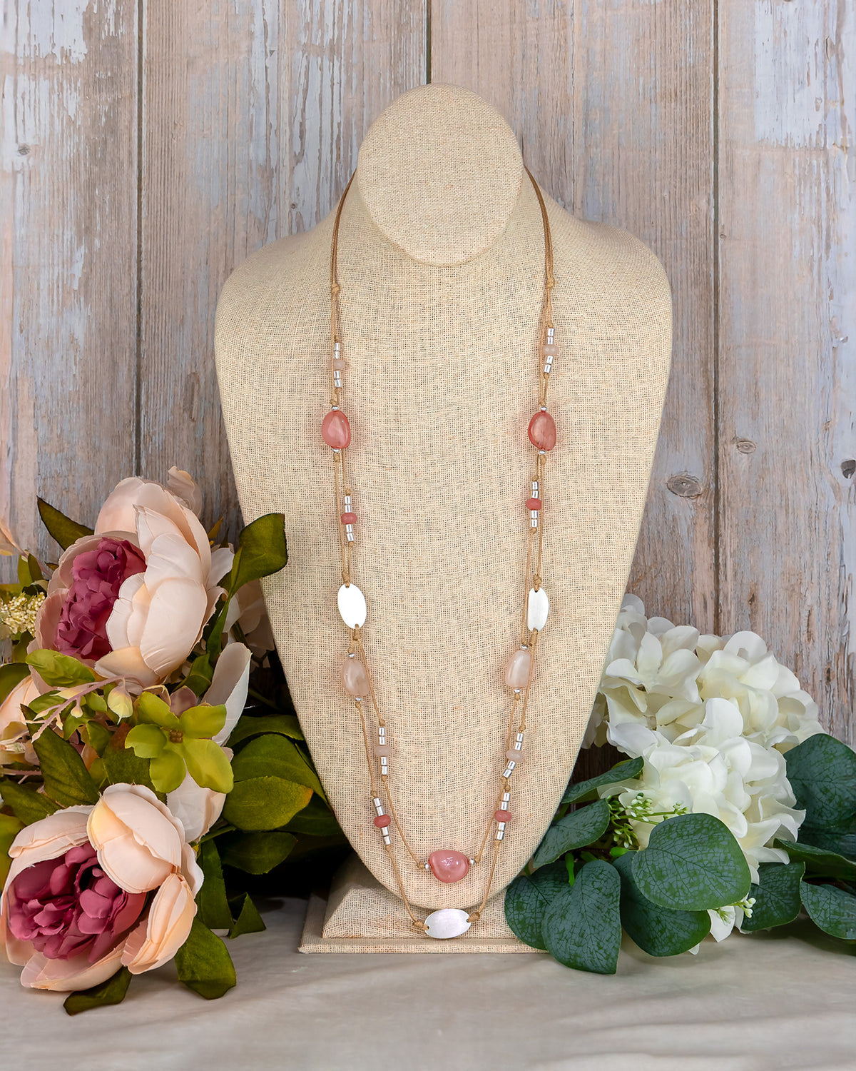 Necklace on a mannequin bust with flowers in the background
