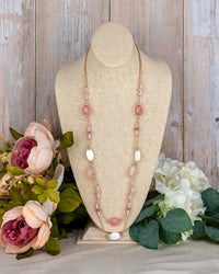 Necklace on a mannequin bust with flowers in the background