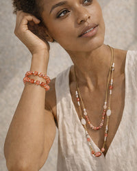 Woman wearing a necklace and bracelet with a neutral background