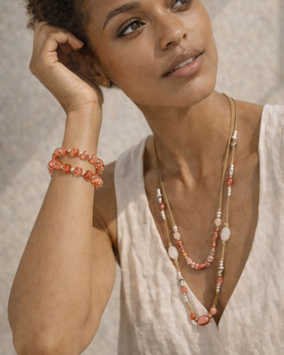 Woman wearing a necklace and bracelet with a neutral background
