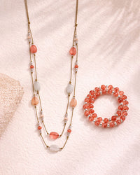 Beaded necklace and bracelet set on a textured pink surface