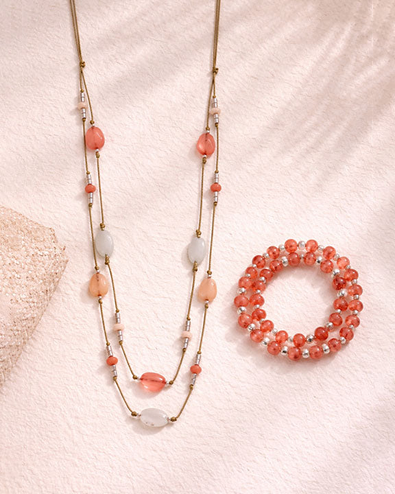Beaded necklace and bracelet set on a textured pink surface