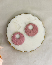 Pink earrings on a white donut with gold rim