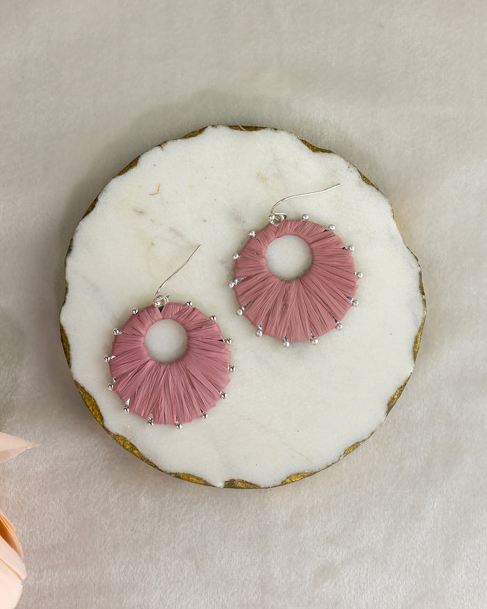 Pink earrings on a white donut with gold rim
