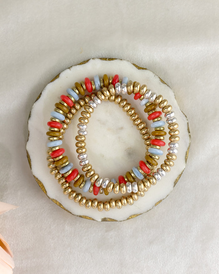 Three beaded bracelets on a decorative stone surface