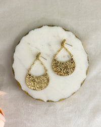 Gold earrings on a white stone surface