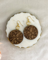 Wooden earrings with gold hooks on a white marble surface