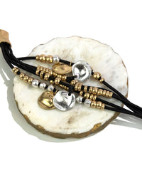 Set of beaded bracelets on a white shell stand with gold and silver accents