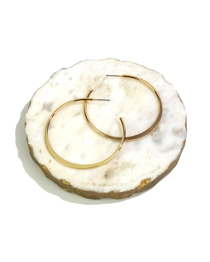 Gold hoop earrings on a white marble surface