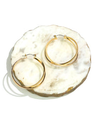 Gold hoop earrings on a textured white surface