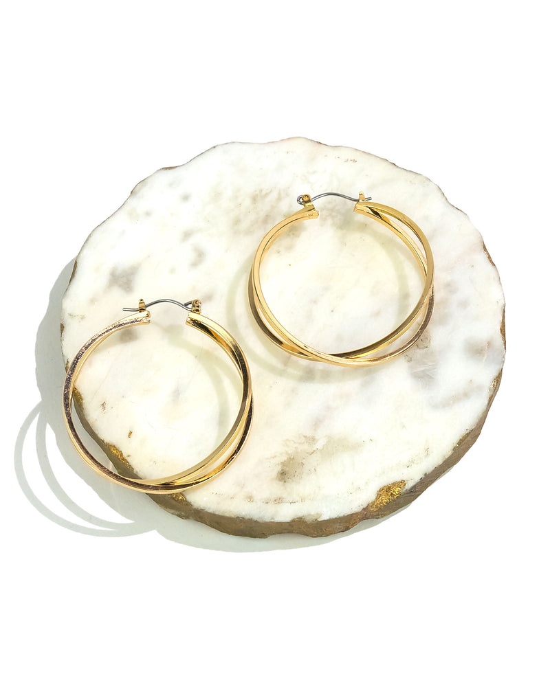 Gold hoop earrings on a textured white surface