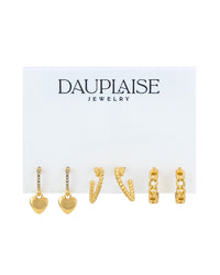 A set of three gold huggie hoop earrings displayed on a white card from Dauplaise Jewelry. The earrings include a pair of small gold heart charms, two textured gold 'heart' shaped hoops, and two gold chain huggies.