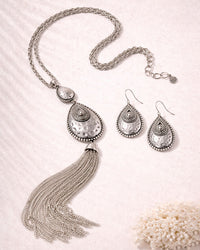 Silver necklace with tassels and matching earrings on a light background