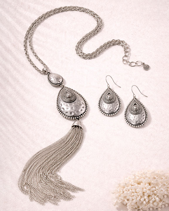 Silver necklace with tassels and matching earrings on a light background