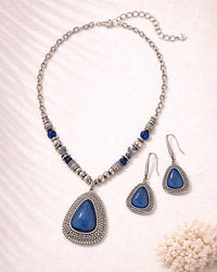 Jewelry set with blue teardrop pendants on a white background