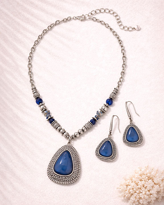 Jewelry set with blue teardrop pendants on a white background