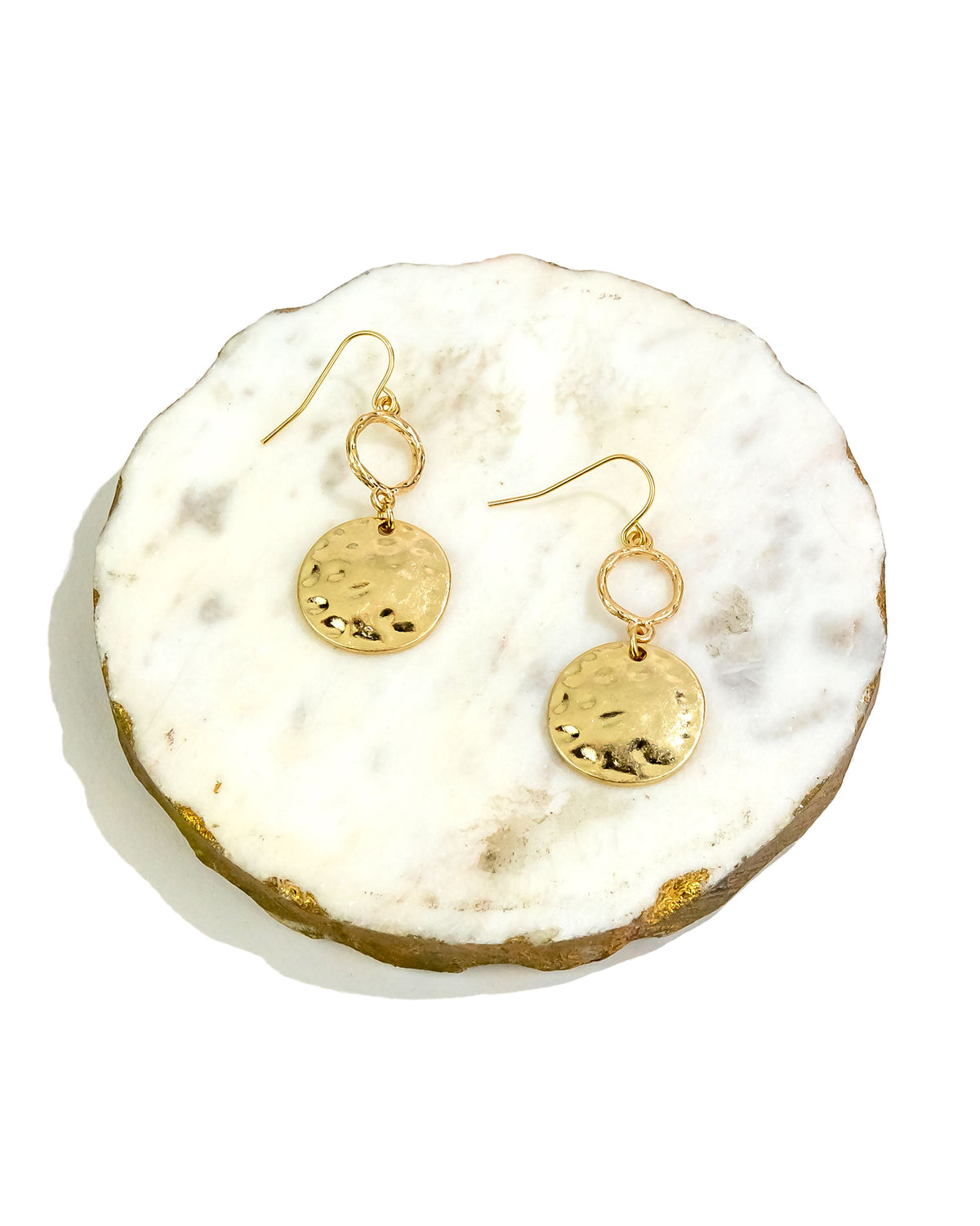 Gold earrings on a white stone surface