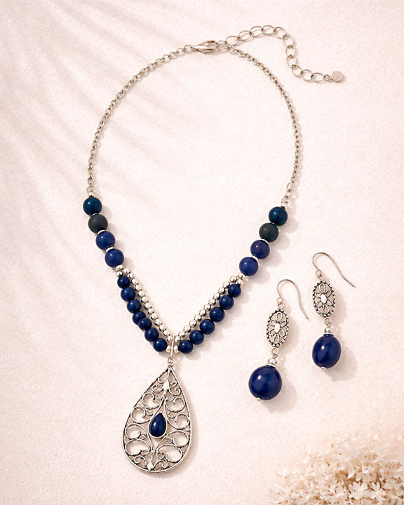 Jewelry set with blue beaded necklace and earrings on a light background