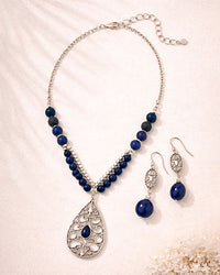 Jewelry set with blue beaded necklace and earrings on a light background