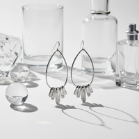 Pear-Shaped Silver Drop Earrings lifestyle shot – glass and shadows